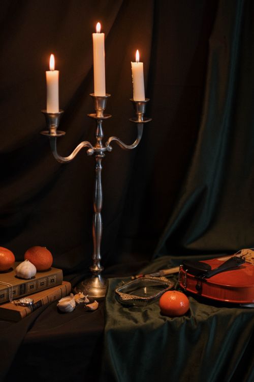 Free Serene still life scene featuring candlelight, violin, and books against a dark backdrop. Stock Photo