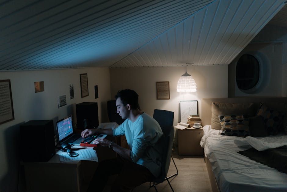 Ultimate Home Automation Routine Setup Myths for 2025 Adult man composing music in a cozy home studio, focused on a laptop and synthesizer under warm ambient lighting.