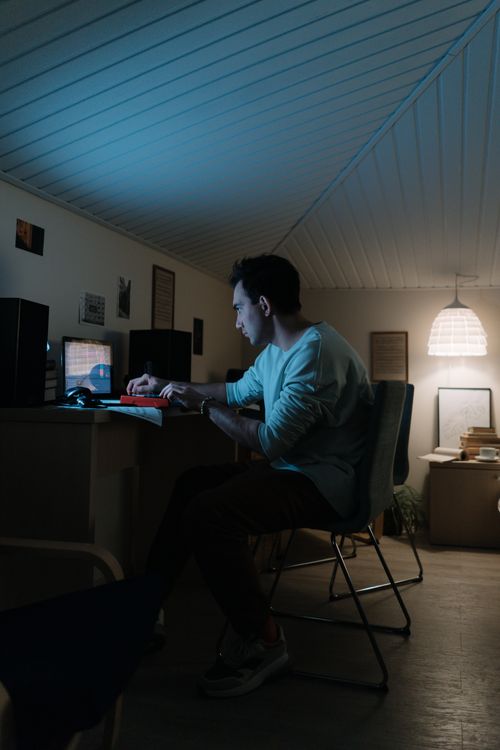 Free Man concentrating late at night in a home office setting, working on a computer. Stock Photo