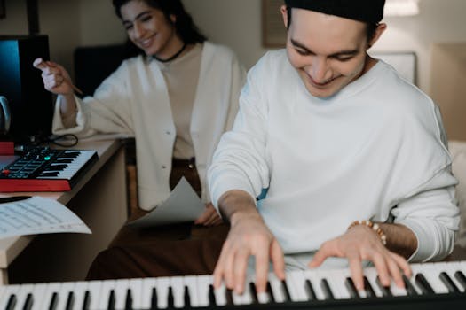 Two young musicians collaborating on a music project in a modern studio with keyboards.