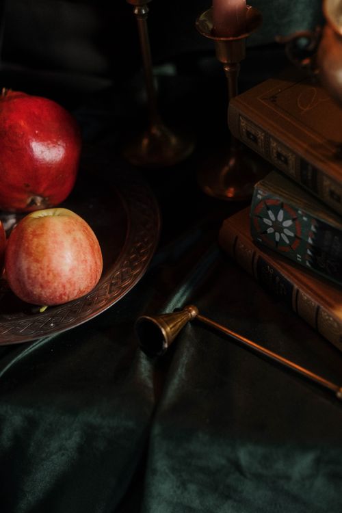 Free Artistic still life featuring apples, books, and brass on rich velvet with a dark, moody tone. Stock Photo