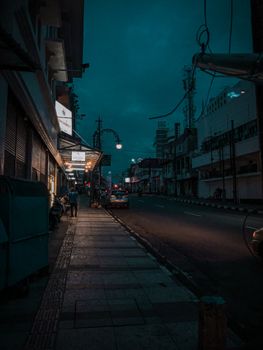 Moody urban night scene showcasing a quiet street with dim streetlights and buildings.