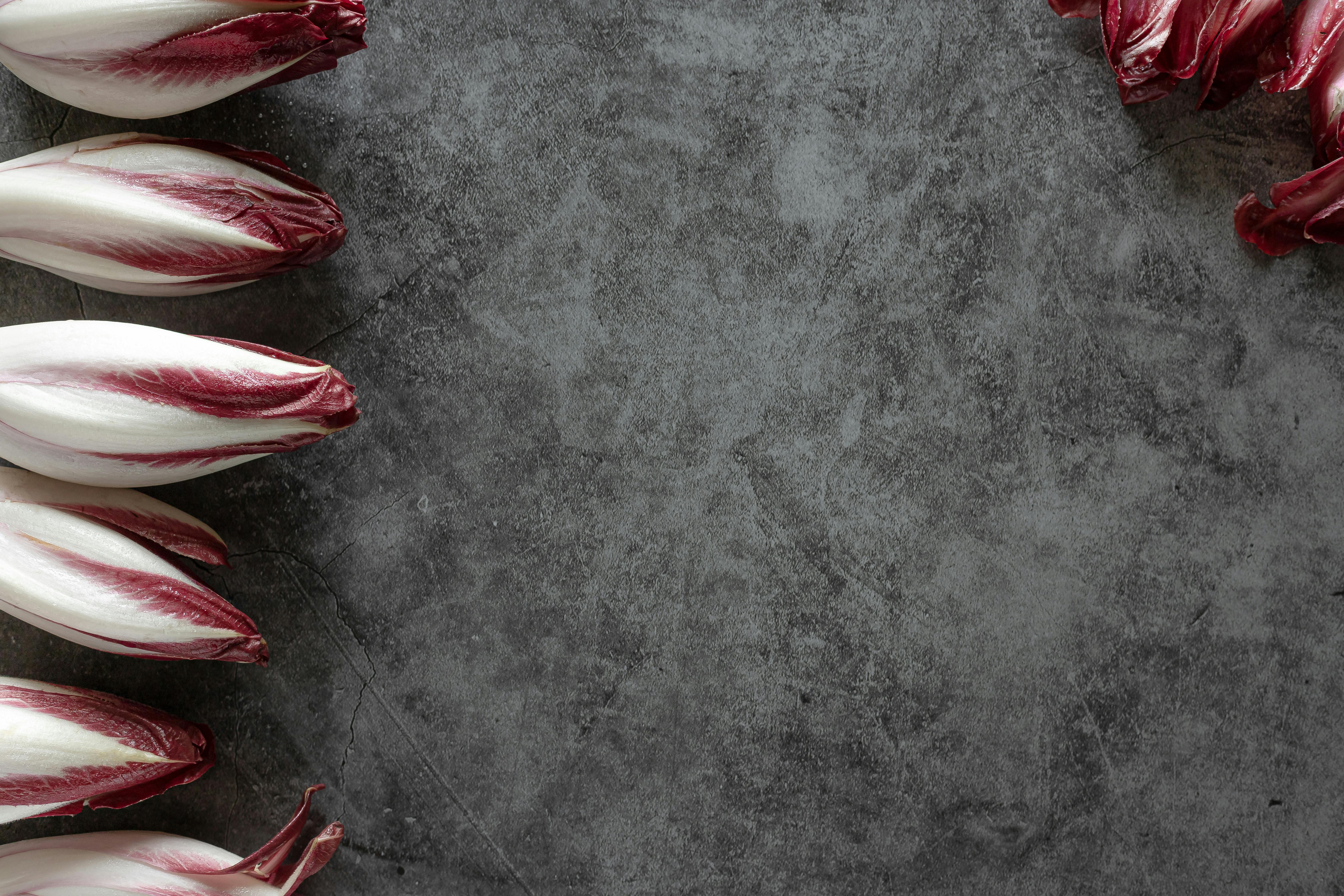 Top view of red Belgian endive leaves on a dark textured background, ideal for food-themed designs.