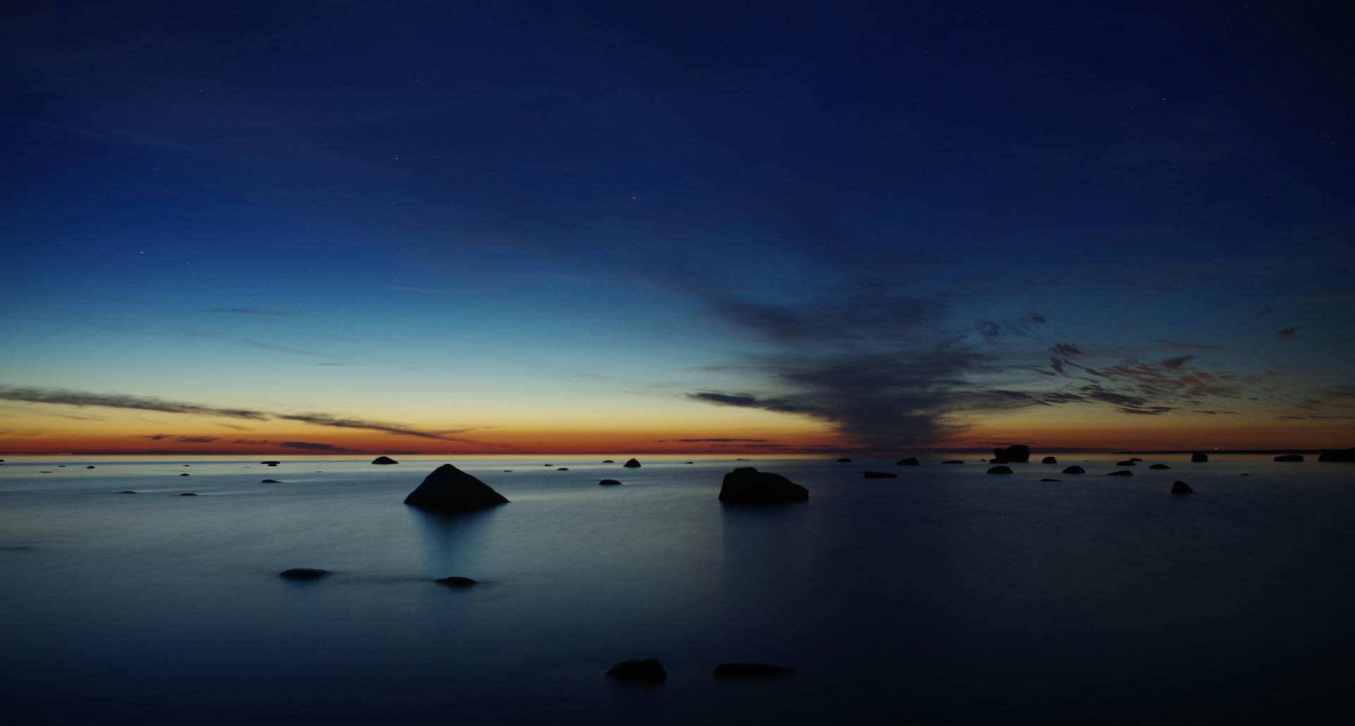 Capture of a serene sunset at Muraste, Estonia with rocks and tranquil waters.