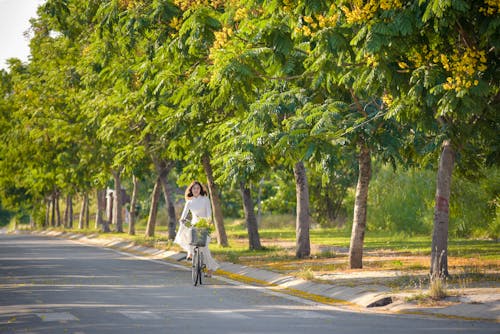 A Woman in White Dress Riding a Bike