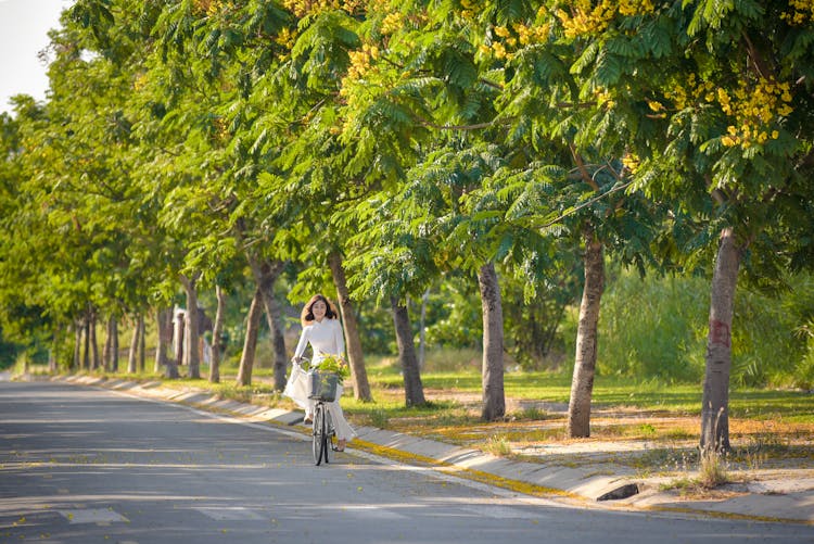 A Woman In White Dress Riding A Bike