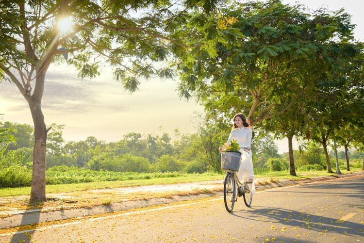 A Woman In White Dress Riding A Bike