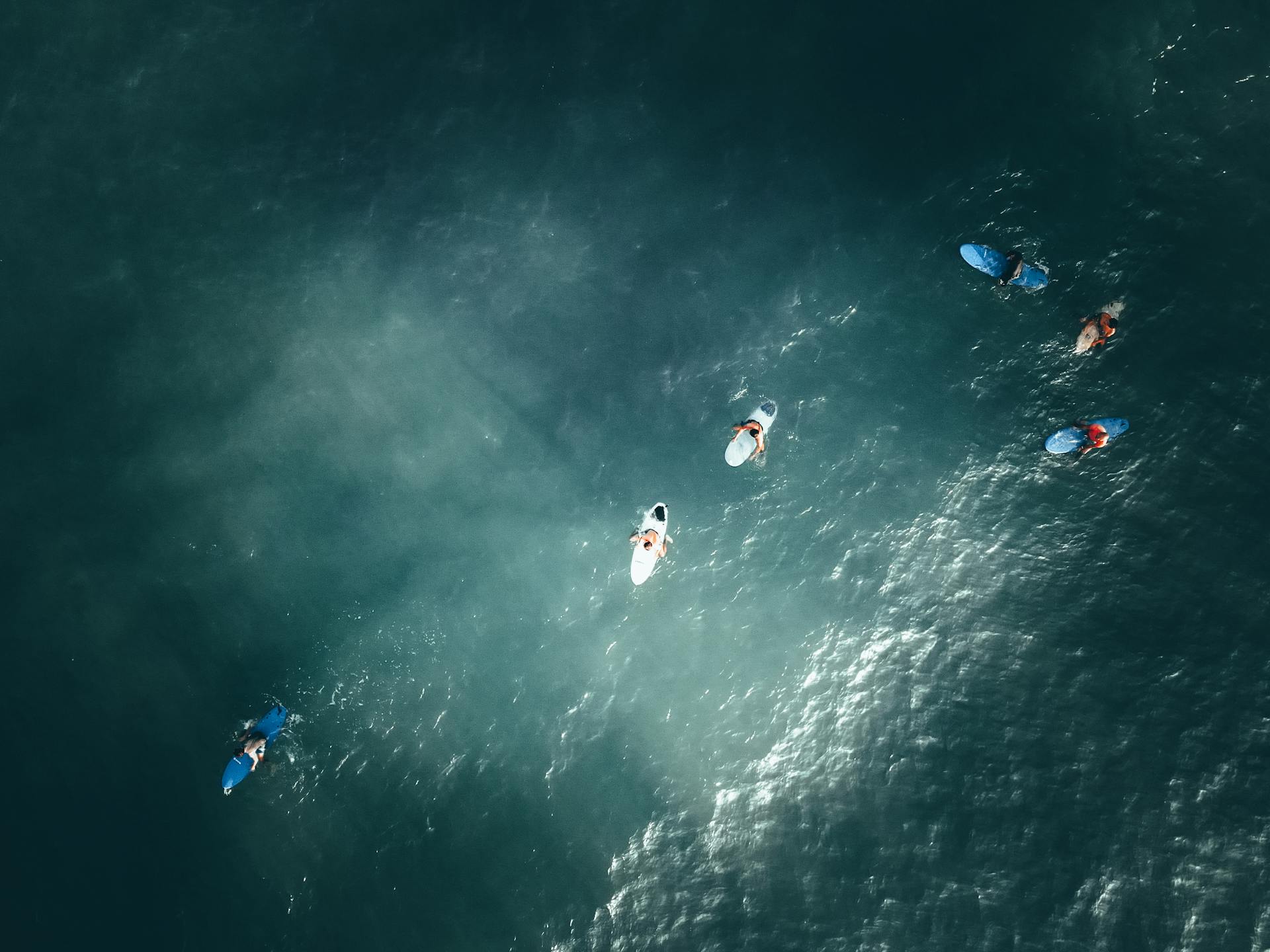 Aerial shot of surfers enjoying the waves in Terengganu, Malaysia under sunlight.