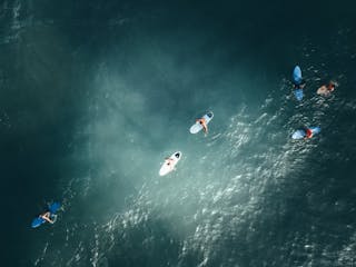 From above of surfers on surfing boards floating in sea water on sunny day