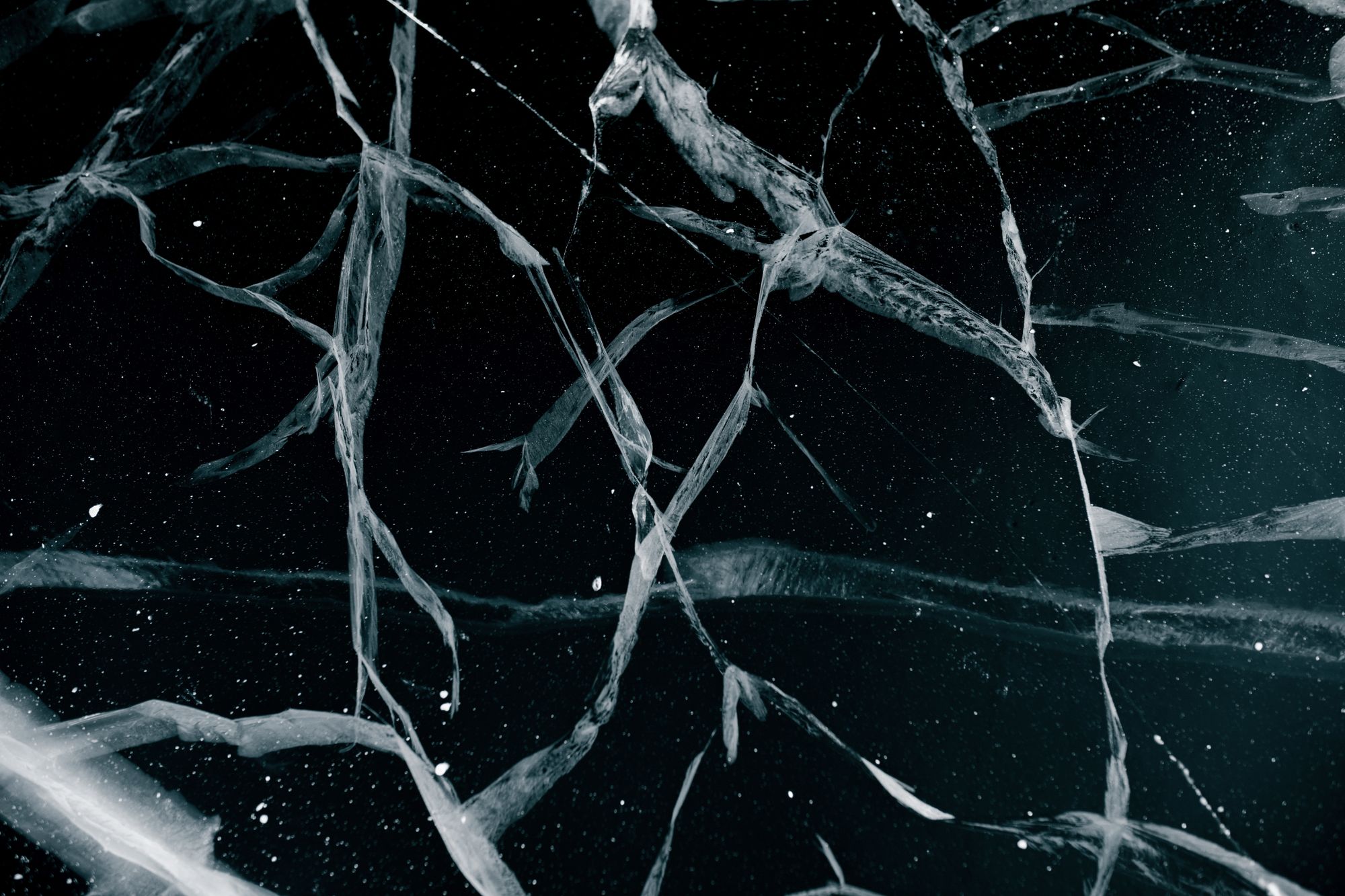 Superficie de hielo agrietada vista de cerca, con fracturas que se cruzan sobre una capa gruesa