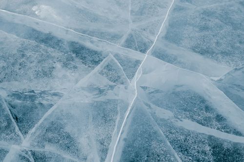 Free A detailed view of cracked ice on a frozen lake during winter, showcasing natural textures. Stock Photo