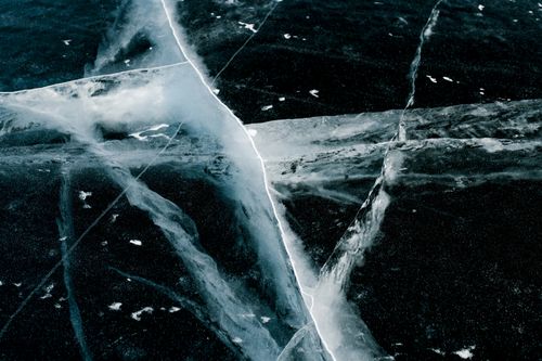 Free Detailed view of cracked ice on a frozen lake with intricate patterns. Stock Photo