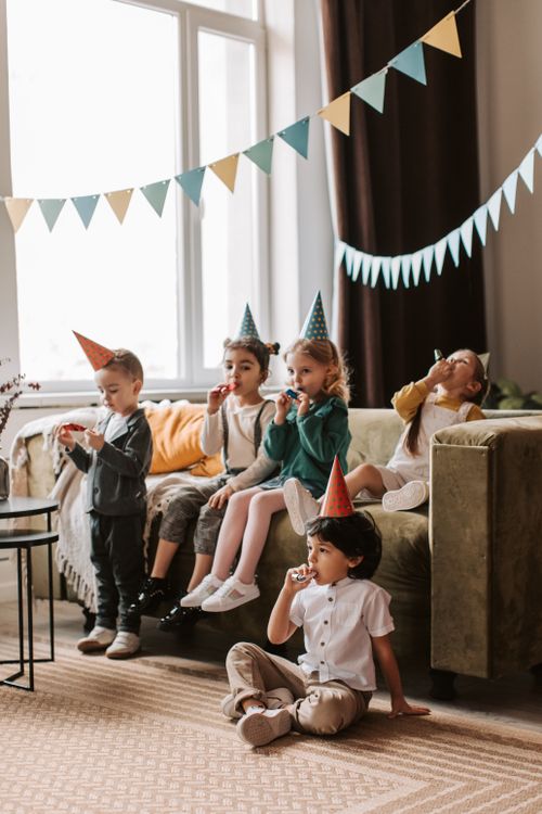 Free Group of kids wearing party hats celebrating a birthday indoors with decorations. Stock Photo
