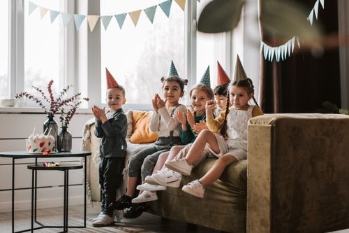 Free A group of kids celebrating a birthday at home with party hats and decorations. Stock Photo