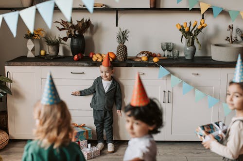 Boy in Gray Sweater Standing Beside White Wooden Cabinets