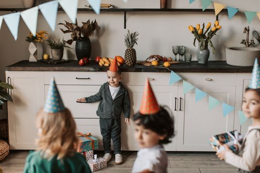 Children enjoying a birthday party indoors with gifts and party hats.