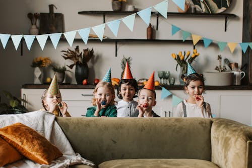 Children Standing Behind Brown Couch