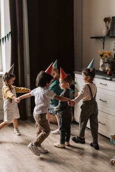 Kids enjoying a birthday party with party hats, dancing indoors around a kitchen counter.