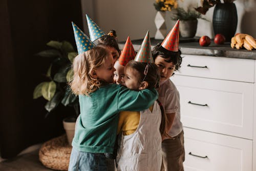 Kids With Party Hats Hugging Each Other 
