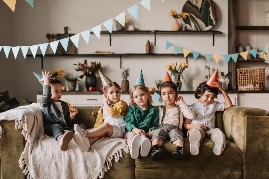 Children enjoying a birthday party with hats and horns indoors