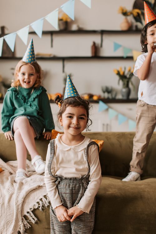 Free Smiling children enjoying a fun birthday party with colorful hats indoors, creating joyful memories. Stock Photo