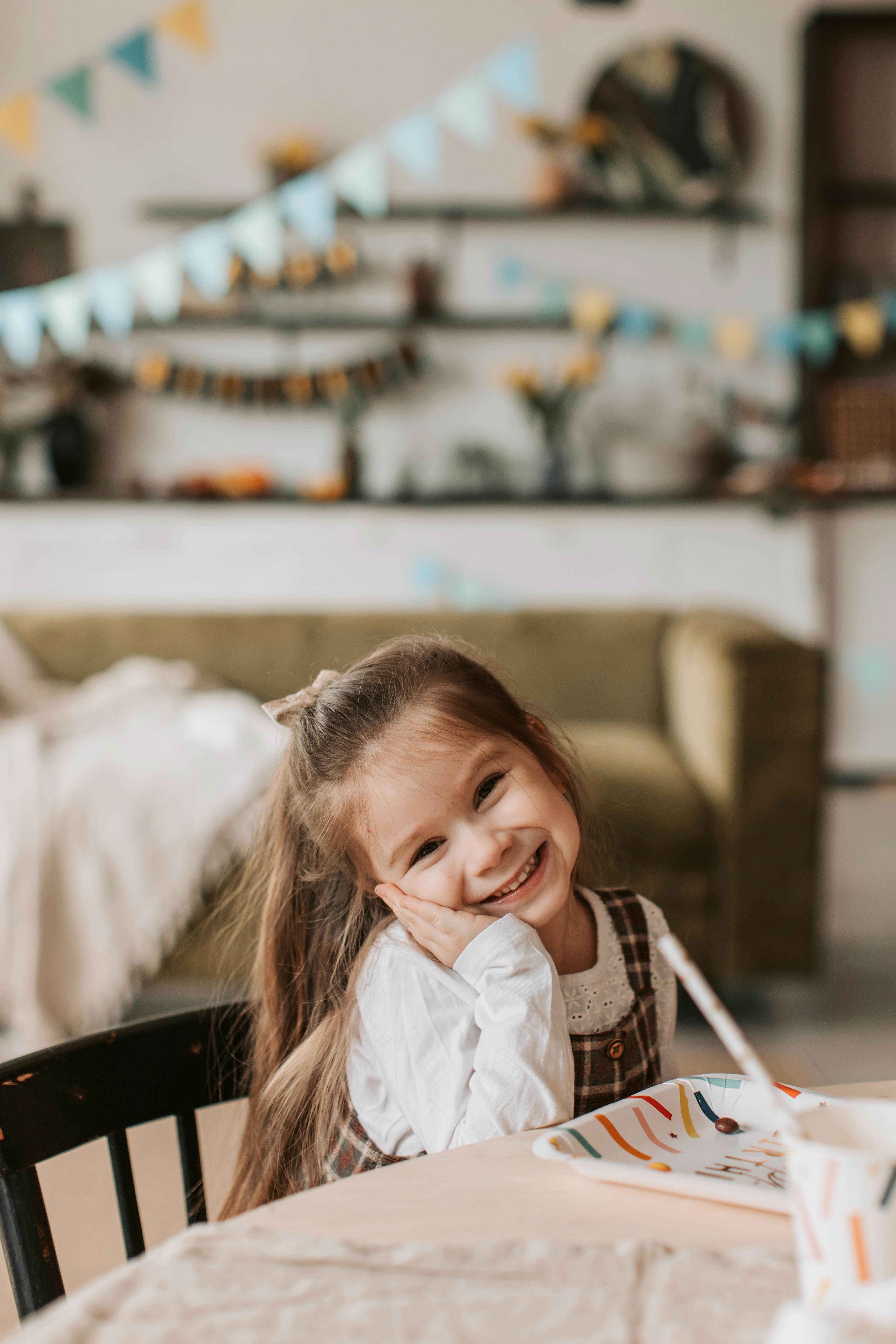 Smiling little girl sitting at a table with empty small chalkboard