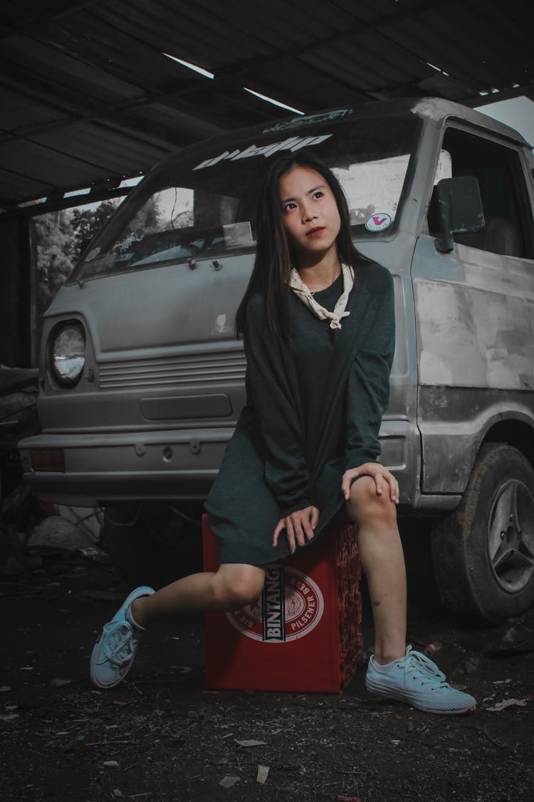 Woman Sitting On A Crate Of Beer Next To A Vintage Car 