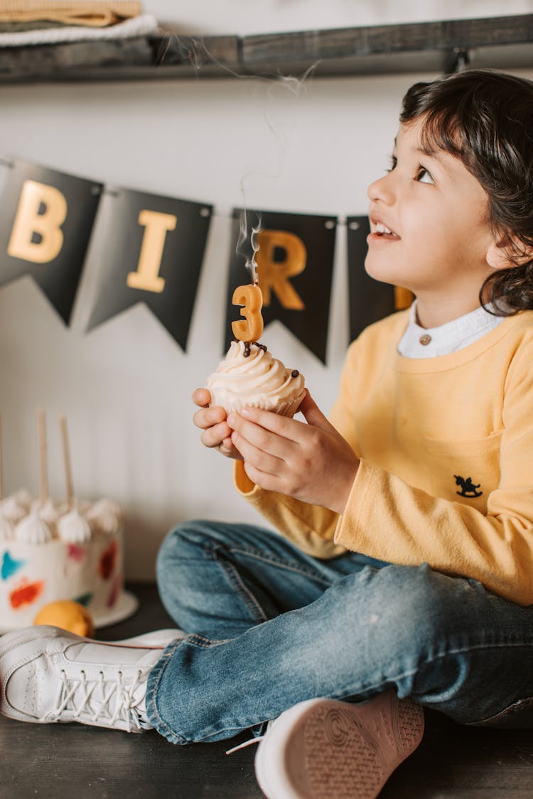 Boy In Yellow Sweater Holding A Cupcake 