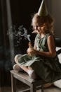 Little Girl in Green Dress Sitting on Wooden Chair