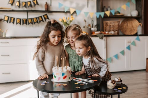 Photograph of Children Blowing the Candles on a Cake