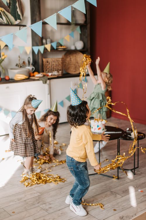 Free Kids in party hats delight in a festive birthday celebration with confetti. Stock Photo