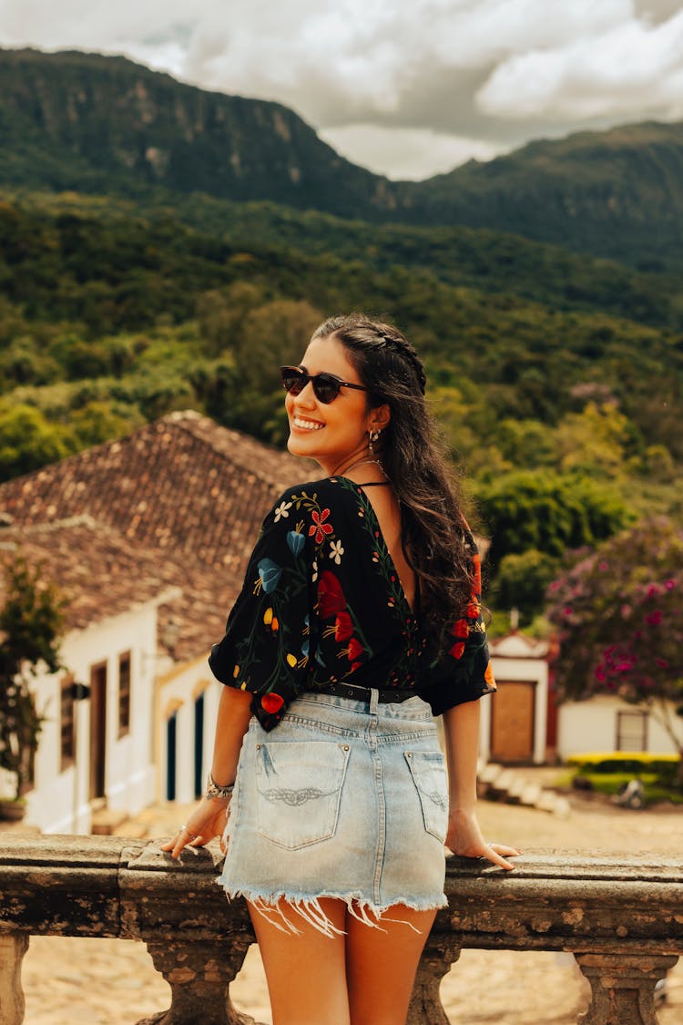 Smiling Girl In Sunglasses With Mountain Village In Background