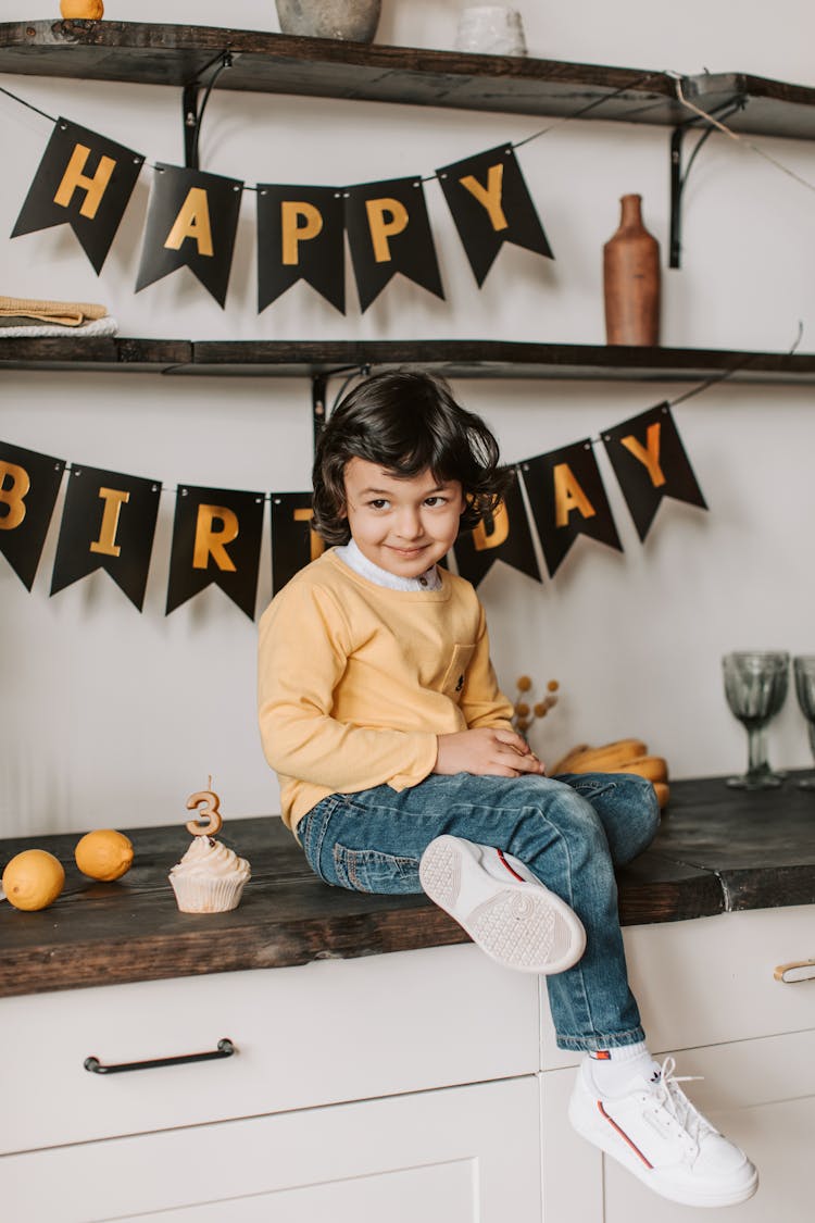 A Kid In A Yellow Shirt Sitting On A Kitchen Counter