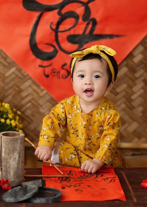 Smiling ethnic toddler painting with brushes on paper