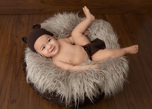 From above of Asian little child lying in soft nest in studio and looking away