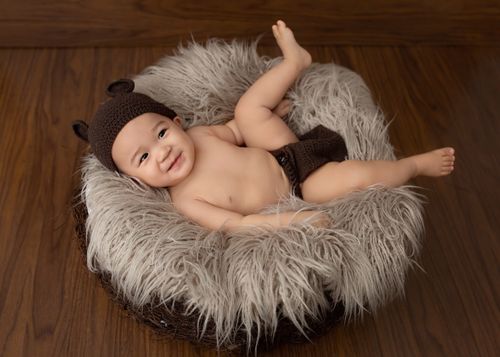 Free From above of Asian little child lying in soft nest in studio and looking away Stock Photo
