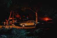 Investigators from police working on crime scene fenced with caution tape in woods at night