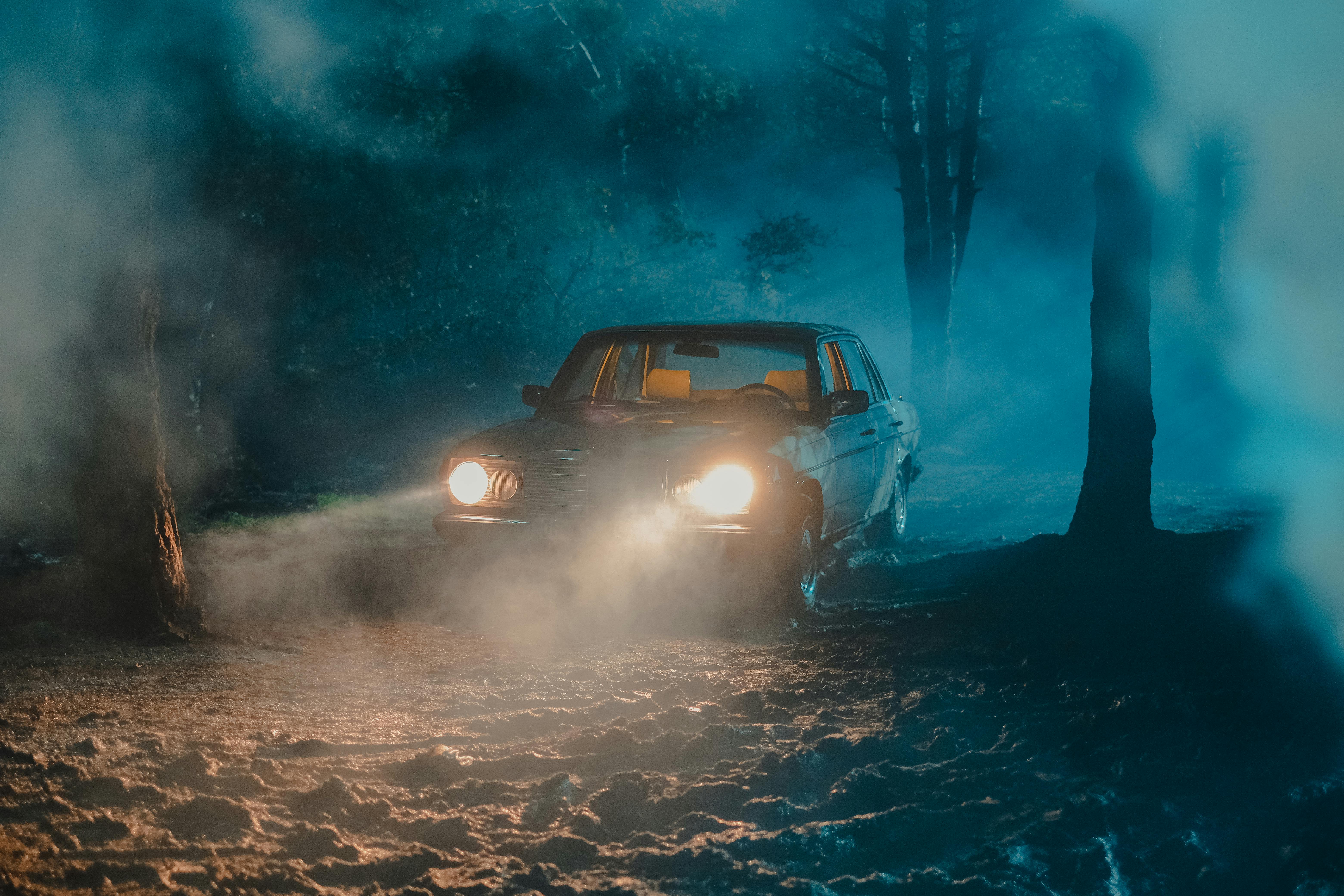 old fashioned car with luminous headlights in dark forest