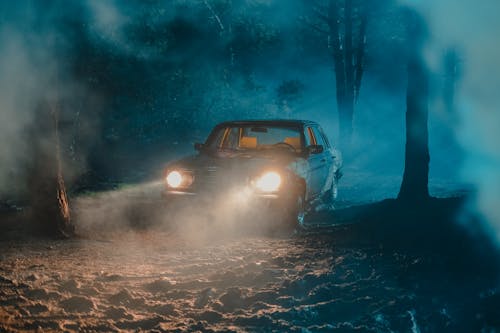 Old fashioned car with luminous headlights in dark forest