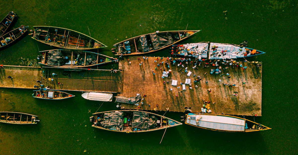 Aerial view of lush green hills and Lake Volta with vibrant fishing boats