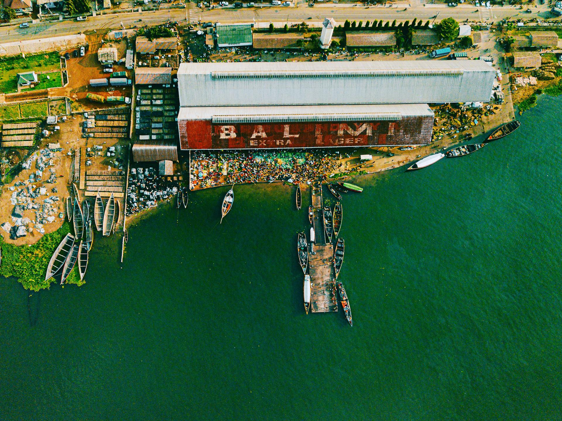 Aerial shot of a bustling port along Lake Victoria in Mwanza, Tanzania, with boats and warehouses.