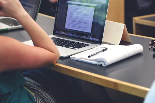 Person Sitting in Front of the Laptop Computer