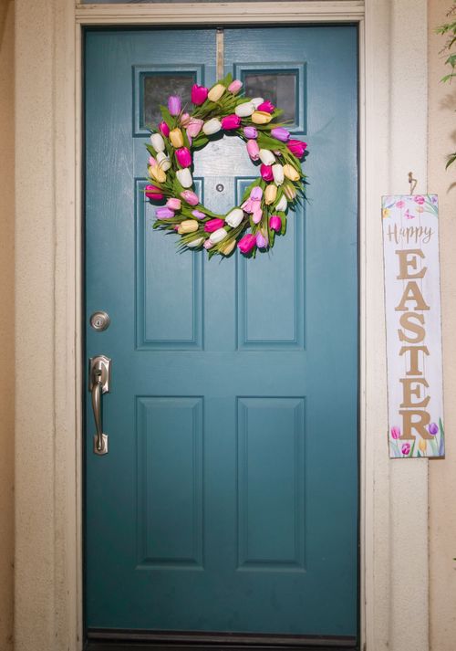 Free Colorful Easter wreath on a blue door with festive happy Easter sign displayed. Stock Photo