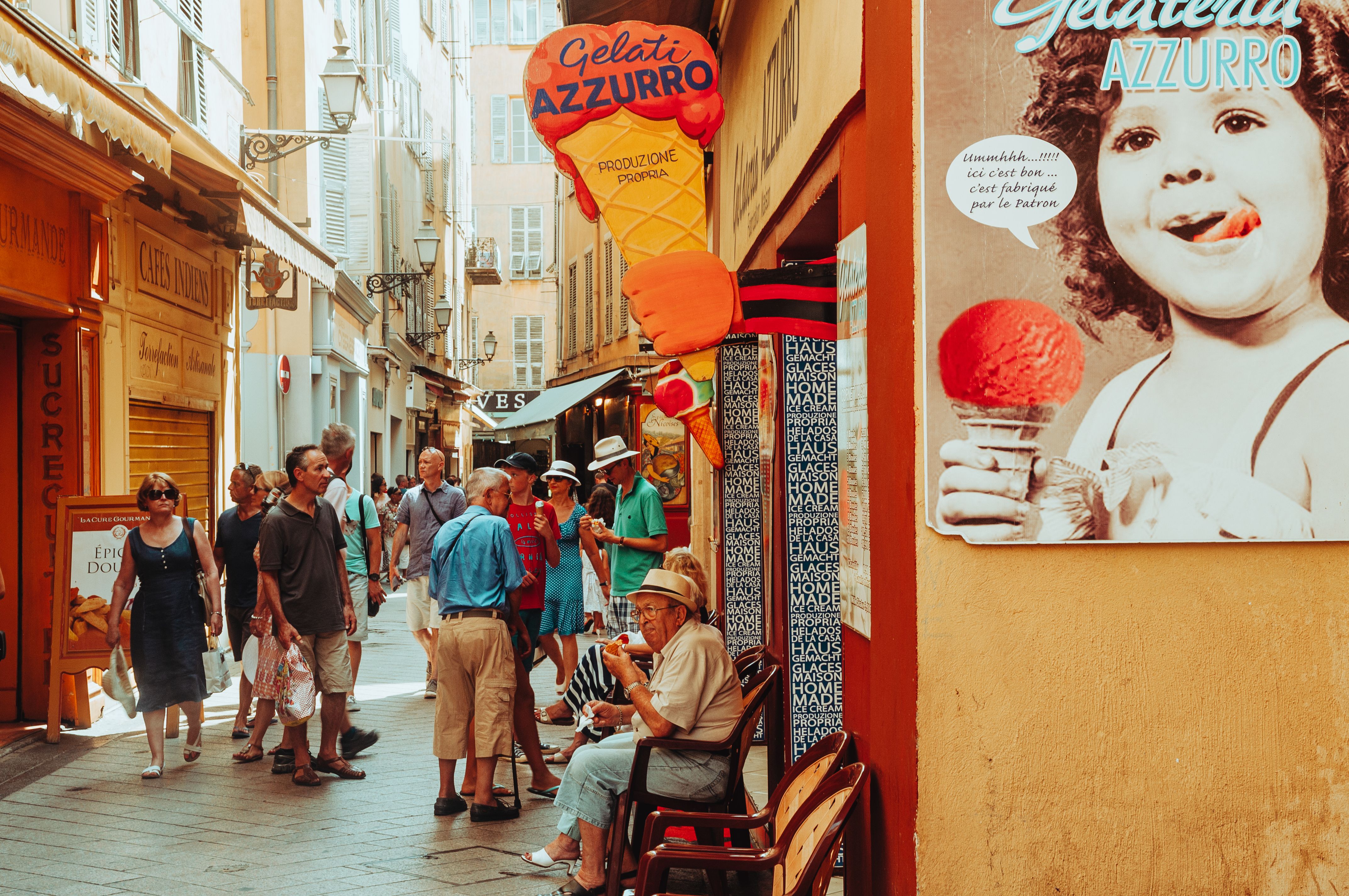 Tourists enjoy a vibrant street market in a French alley with shops and a gelato stand under warm daylight. Tourists enjoy a vibrant street market in a French alley with shops and a gelato stand under warm daylight.