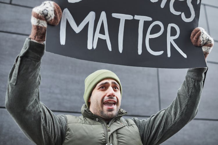 A Man Holding A Protest Sign