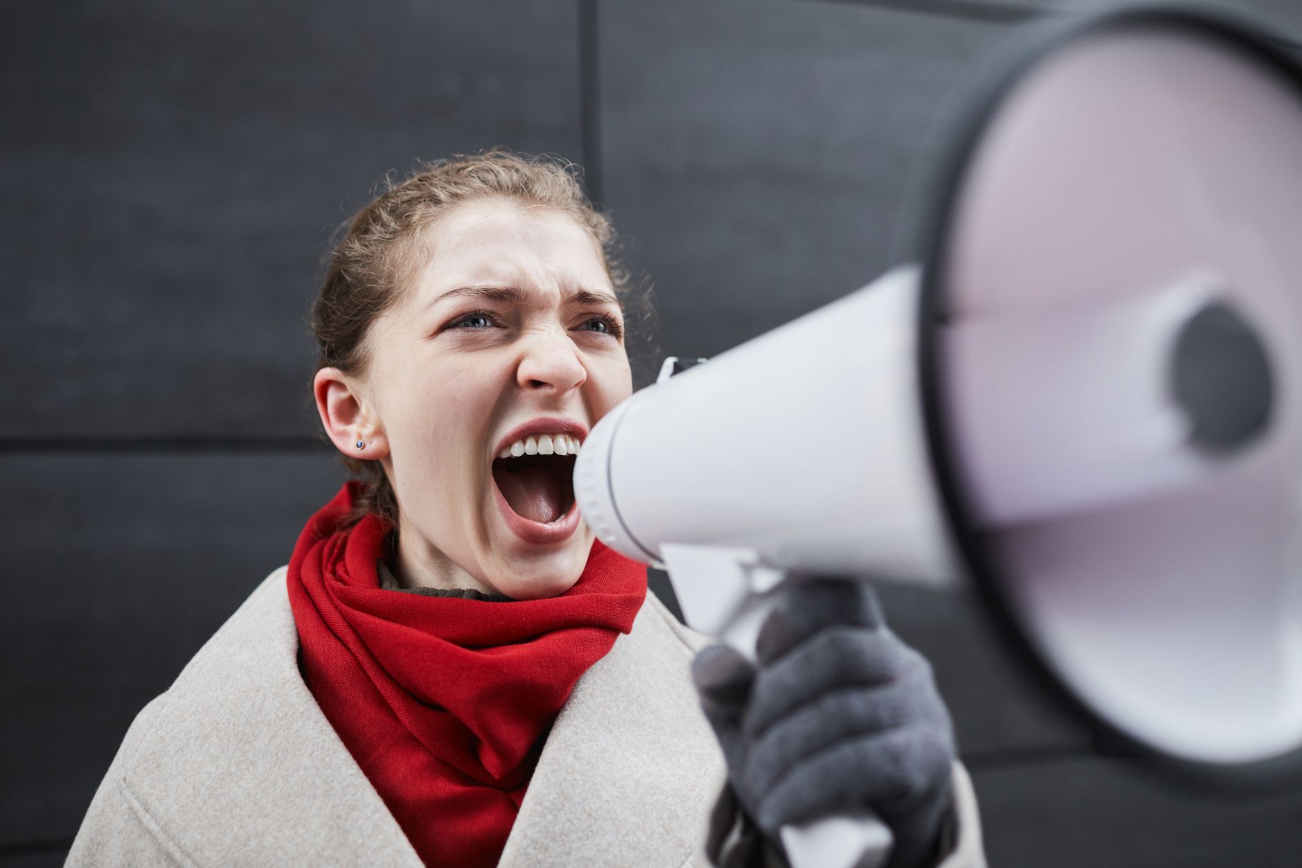 Woman passionately shouting into a megaphone during an outdoor protest.