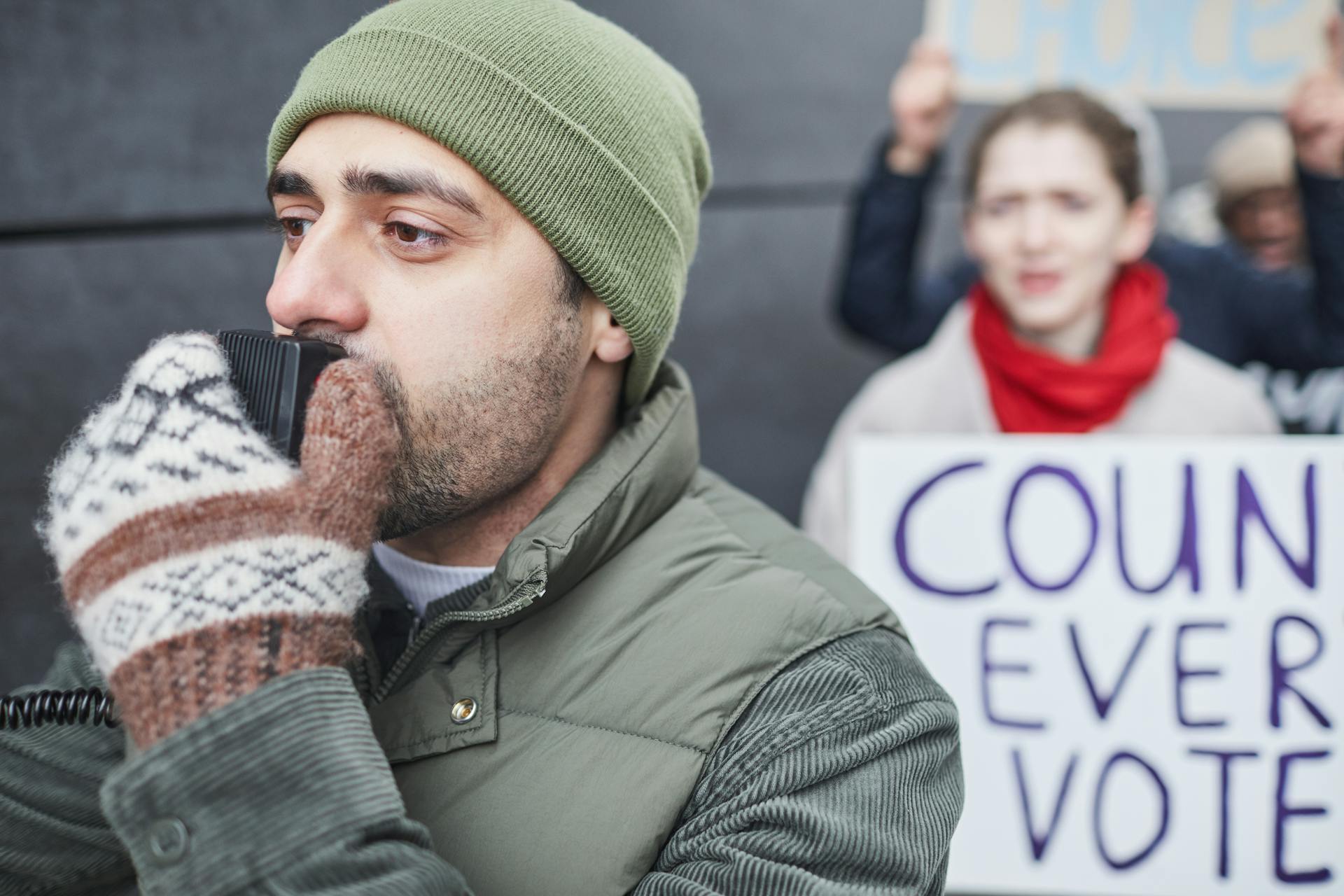 A Man with a Beanie Hat Speaking at a Rally