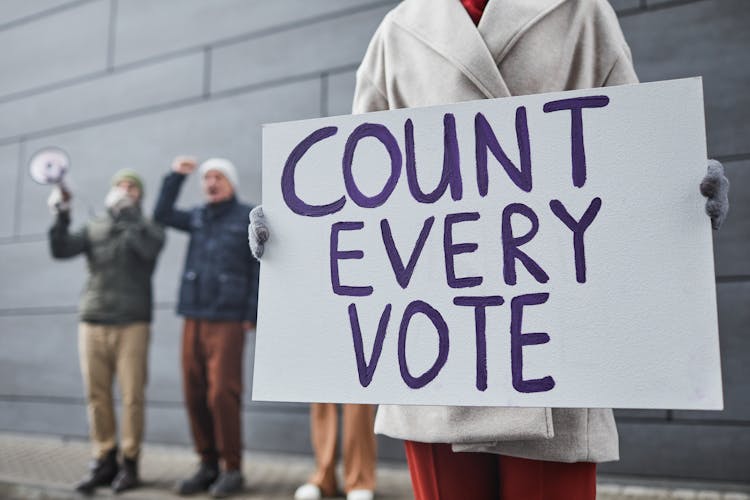 A Person Holding A Poster In A Rally