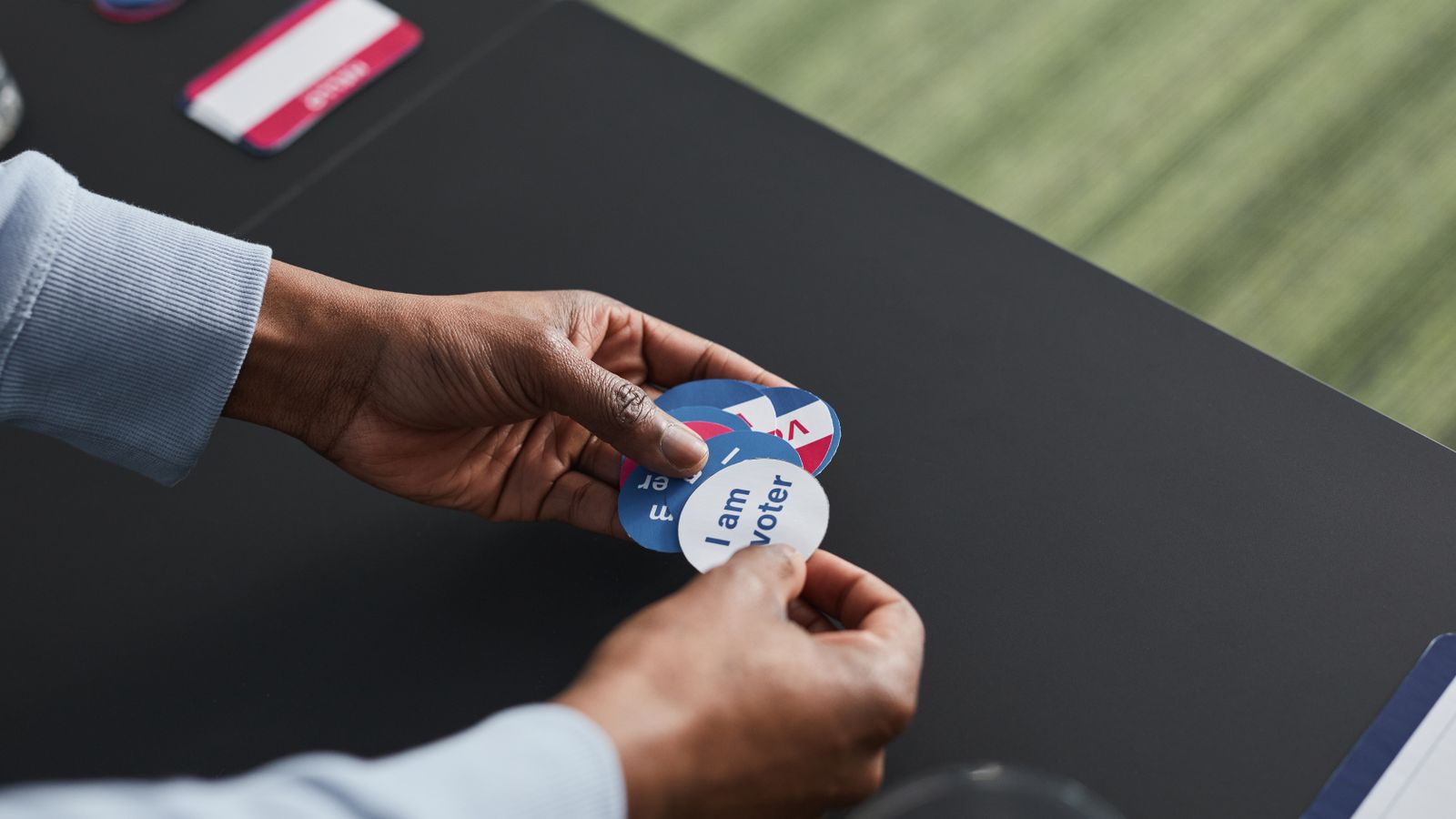 A close-up of hands holding voter stickers, symbolizing civic engagement.