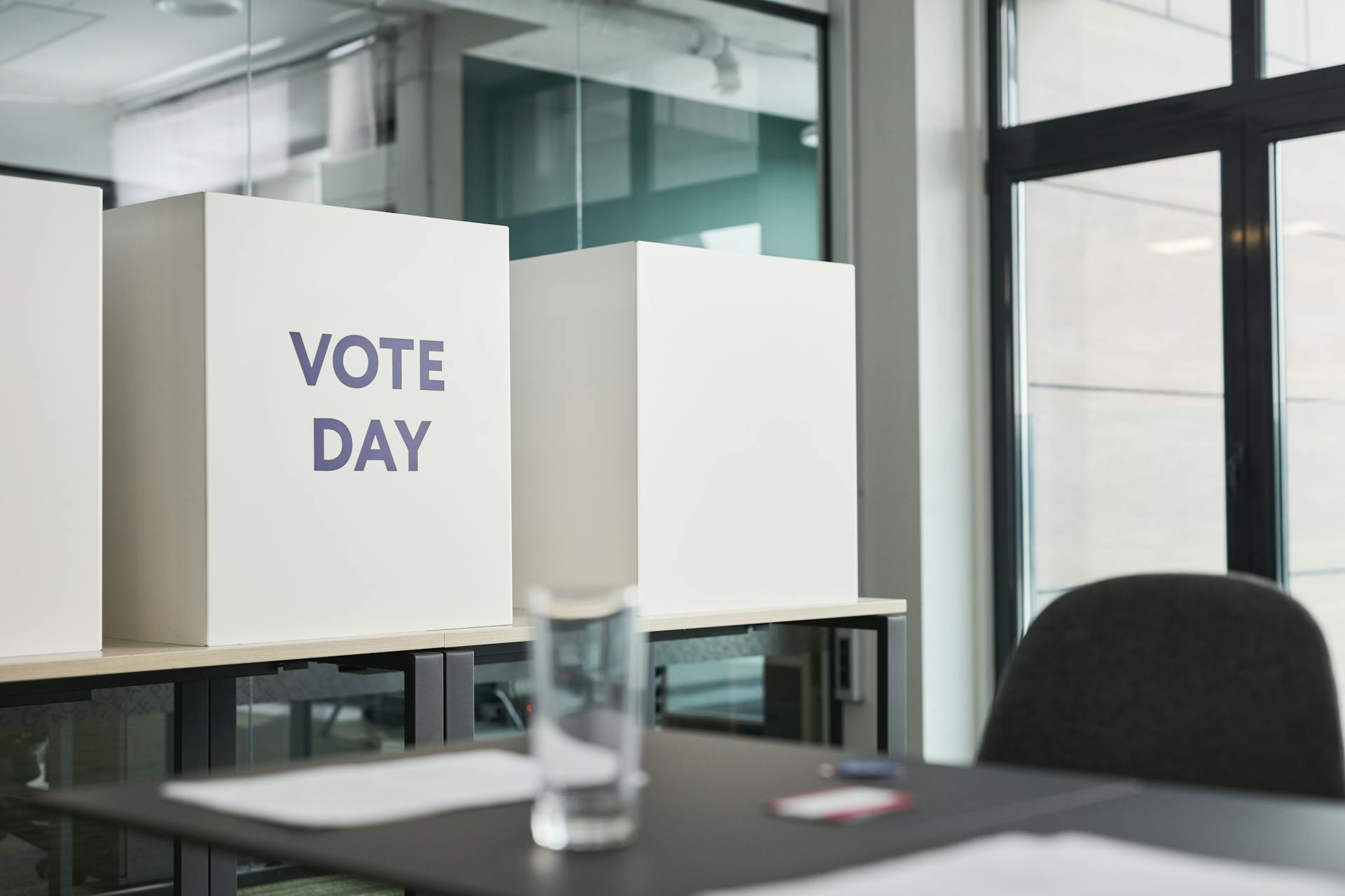 A modern office with voting booths labeled 'Vote Day' indicating election activity.